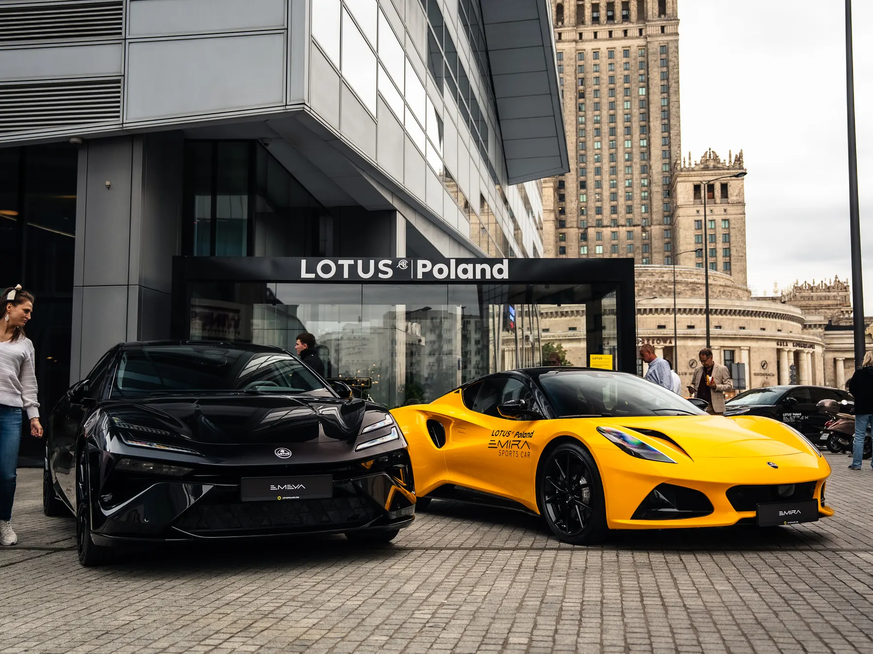Lotus Emeya and Lotus Emira in front of the Lotus Poland pavilion at Złota 44, with the Palace of Culture and Science in the background